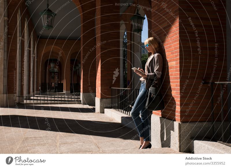 Geschäftsfrau mit Tablette an der Wand stylisch jung Frau Browsen zuschauend Lehnen Backsteinwand professionell Person schön attraktiv Sonnenbrille Wegsehen