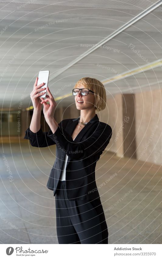 Geschäftsfrau benutzt Smartphone im Flur stylisch jung Frau Stehen Saal Selfie benutzend Browsen unter professionell Person schön attraktiv Unternehmer elegant