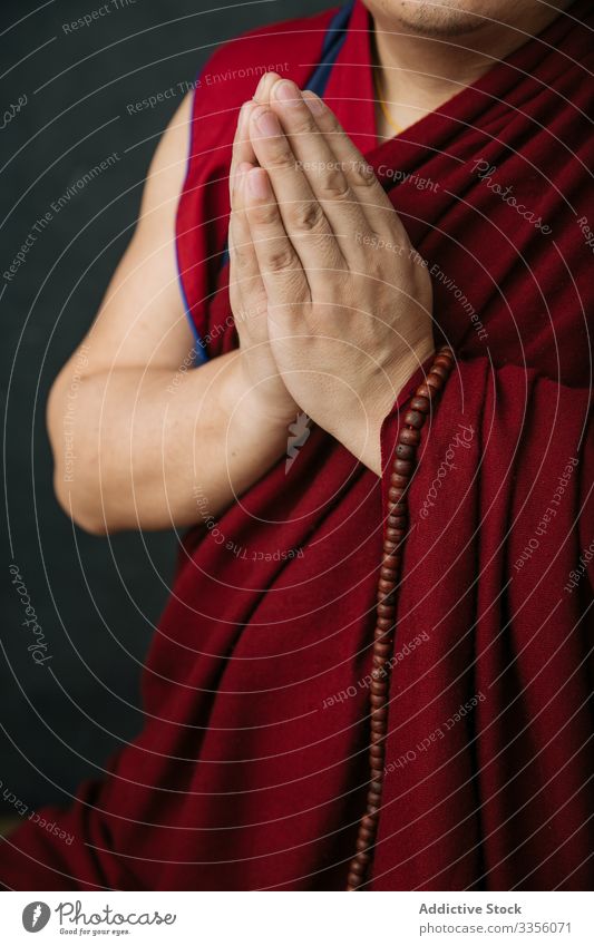 Betender buddhistischer Mönch mit gefalteten Händen gestikulieren beten Religion Mudra Namaste Symbol traditionell Perlen Rosenkranz Tibet rot Kultur