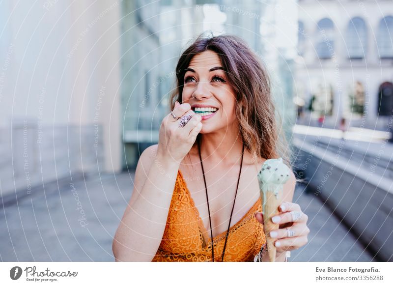 Hübsche junge kaukasische Frau, die an einem sonnigen Tag auf der Straße der Stadt Minzeis isst. Glückliches Gesicht lächelt. Urbane und sommerliche Lebensweise
