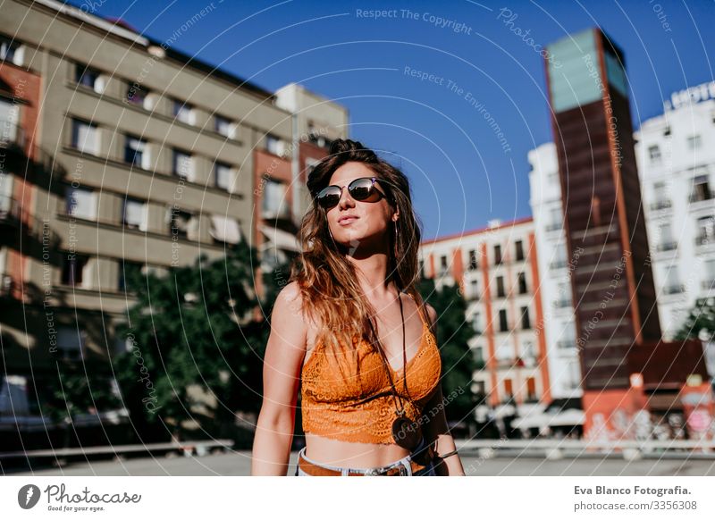 Hübsche junge kaukasische Frau, die an einem sonnigen Tag auf der Straße der Stadt spazieren geht. Glückliches Gesicht lächelt. Urbaner Lebensstil schön