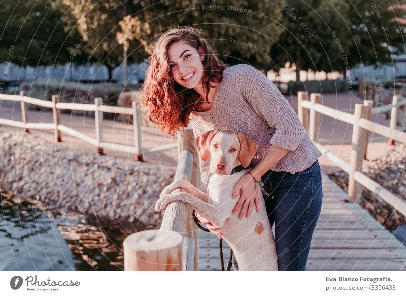 junge Frau und ihr Hund im Freien beim Spaziergang an einer Holzbrücke in einem Park mit See. sonniger Tag, Herbstzeit Porträt Jugendliche Außenaufnahme Liebe