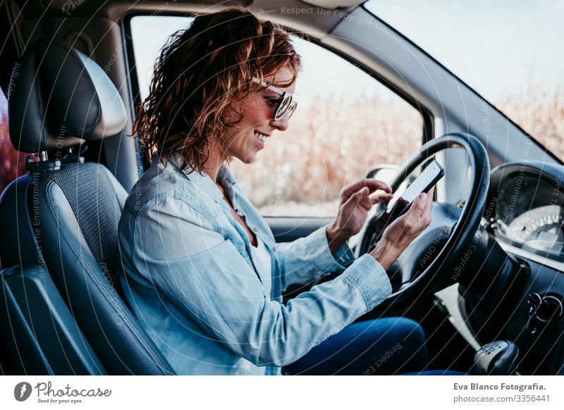 junge, schöne Frau, die im Auto mobil telefoniert. reisekonzept Handy Technik & Technologie benutzend Jugendliche fahren PKW Sonnenstrahlen Sonnenbrille