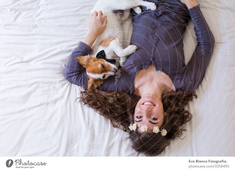 eine schöne junge Frau, die mit ihrem süßen kleinen Hund auf dem Bett liegt. Haus, Wohnung und Lebensstil gemütlich Müdigkeit träumen Stimmung kuscheln