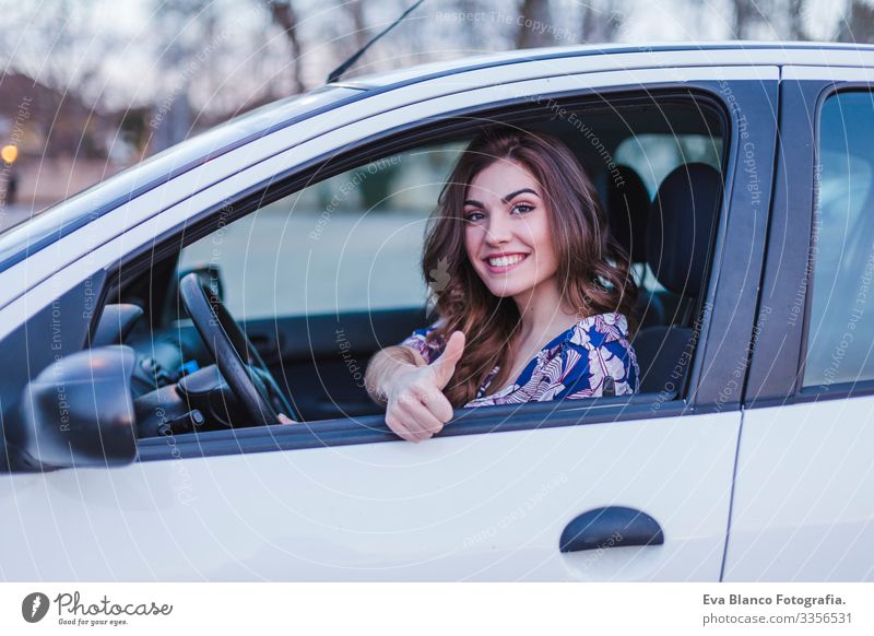 Junge Frau fährt ein Auto in der Stadt. Porträt einer schönen Frau in einem  Auto, die aus dem Fenster schaut und lächelt. Reisen und Urlaub Konzepte -  ein lizenzfreies Stock Foto von
