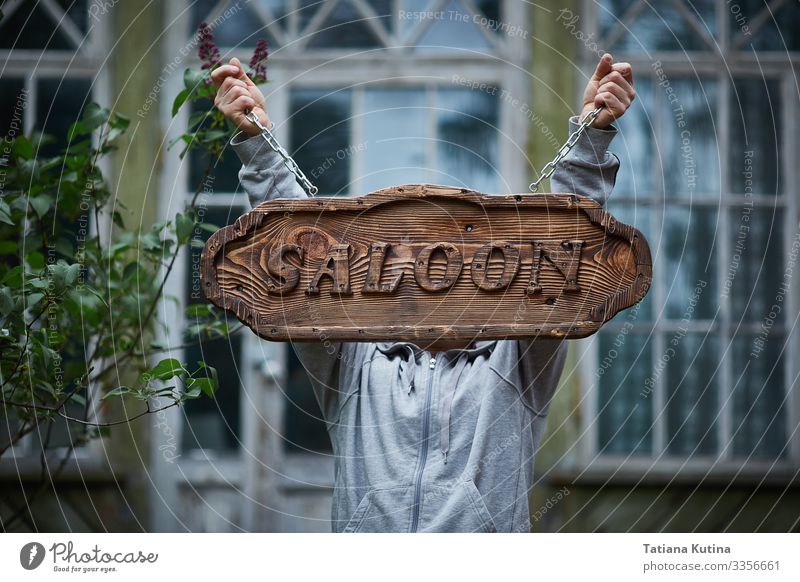 Die Hände des Mannes halten ein Schild mit der Aufschrift "Salon". Alkohol kaufen Ferien & Urlaub & Reisen Tourismus Haus Business Stadt Gebäude Straße Holz