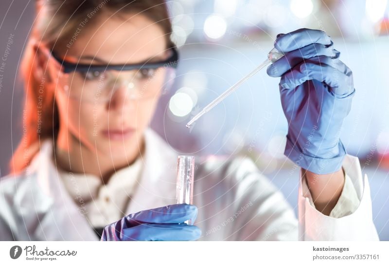 Biowissenschaftler, die im Labor forschen. Fokussierte weibliche Wissenschaftsprofis pipettieren Lösung in Glasküvette. Fokussierung der Linse auf die Pipette. Gesundheitswesen und Biotechnologie. Graustufenbild mit Blauton.
