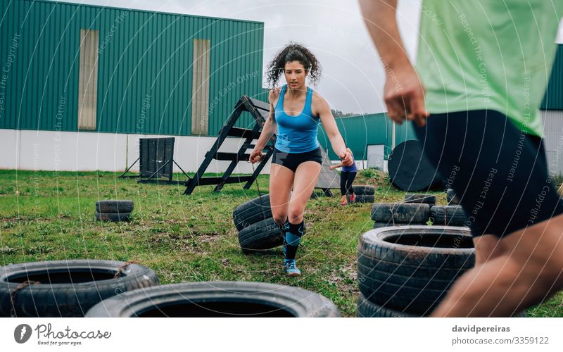 Weibliche Teilnehmerin im Hindernislauf, die Räder zieht Sport Mensch Frau Erwachsene Mann Gras authentisch stark Kraft anstrengen Hindernisrennen schleppend
