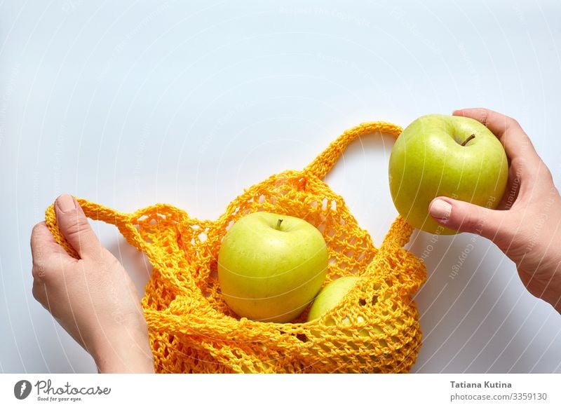 Eine weibliche Hand legt Äpfel in einen gelben Fadenbeutel. Lebensmittel Gemüse Apfel Ernährung Diät Lifestyle kaufen Mensch Frau Erwachsene stehen tragen