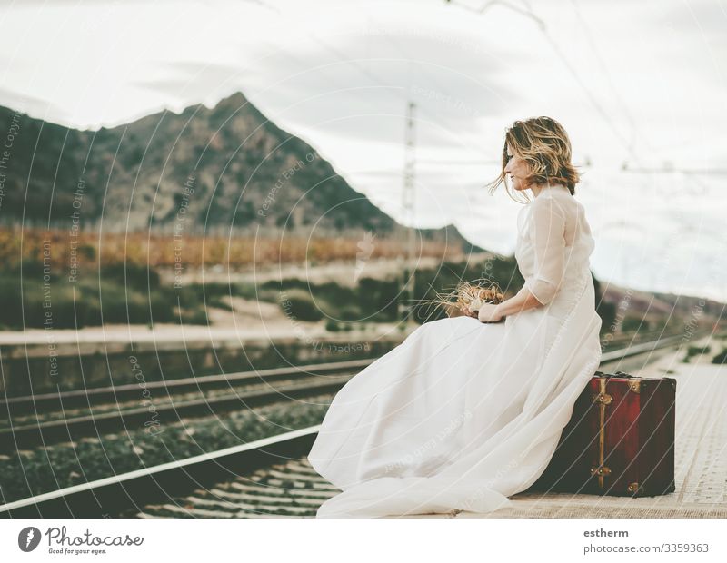 Nachdenkliche Braut mit einem roten Koffer auf den Bahngleisen im Freien Lifestyle elegant Stil schön Ferien & Urlaub & Reisen Abenteuer Freiheit Hochzeit