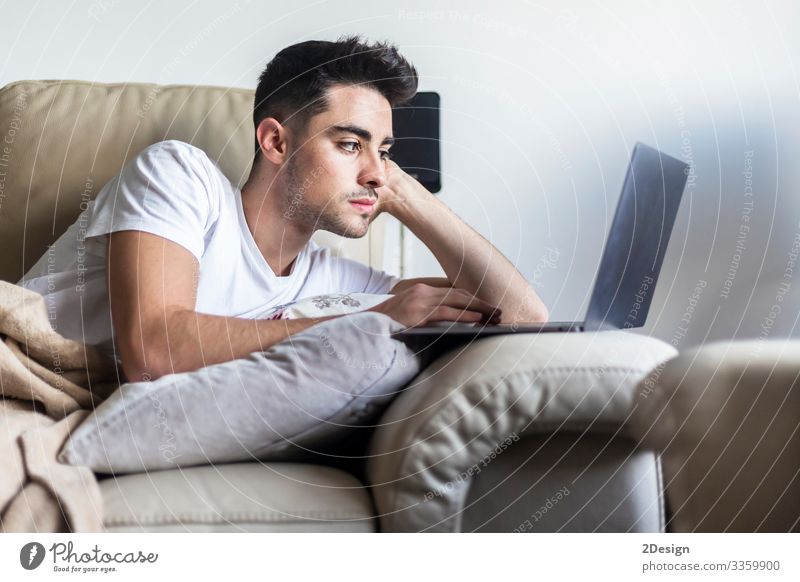 Junger männlicher Mann entspannt sich auf dem Sofa, während er einen Laptop benutzt Lifestyle Glück Erholung Freizeit & Hobby Haus Wohnzimmer