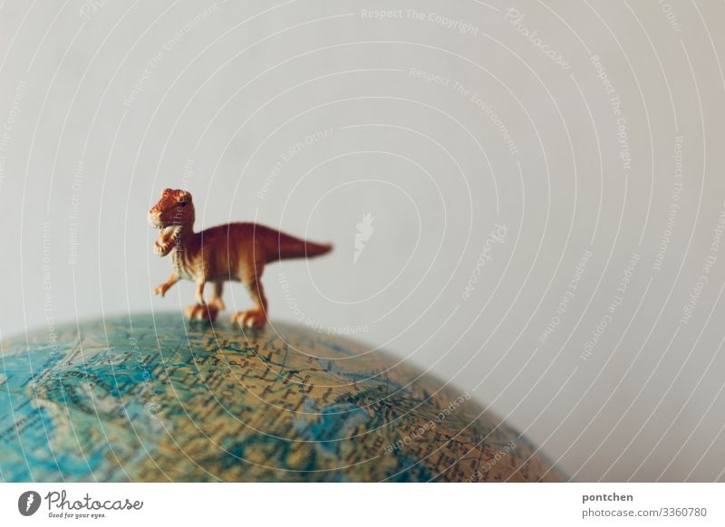 Dinosaurierfigur T-Rex auf Globus Klimawandel Wildtier 1 Tier Aggression alt ausgestorben Meteor Erde Figur Spielzeug bedrohlich Fleischfresser Farbfoto