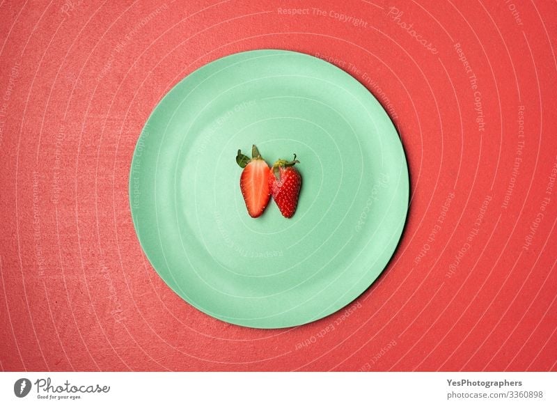 Eine halbierte Erdbeere auf grünem Teller Lebensmittel Frucht Dessert Süßwaren Ernährung Frühstück Bioprodukte lecker natürlich obere Ansicht Beeren Entwurf