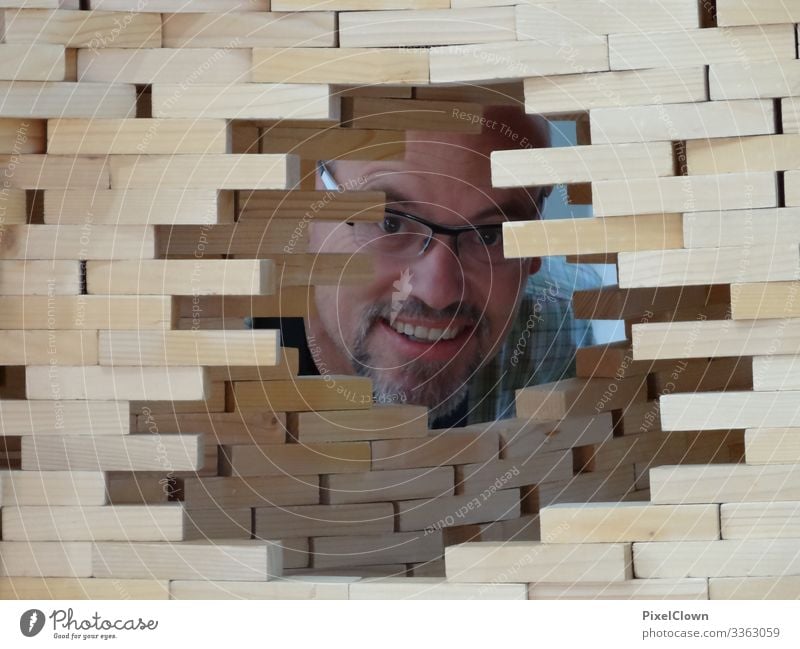 Ein Mann schaut durch eine Mauer Mensch Brille maskulin Bart Kopf