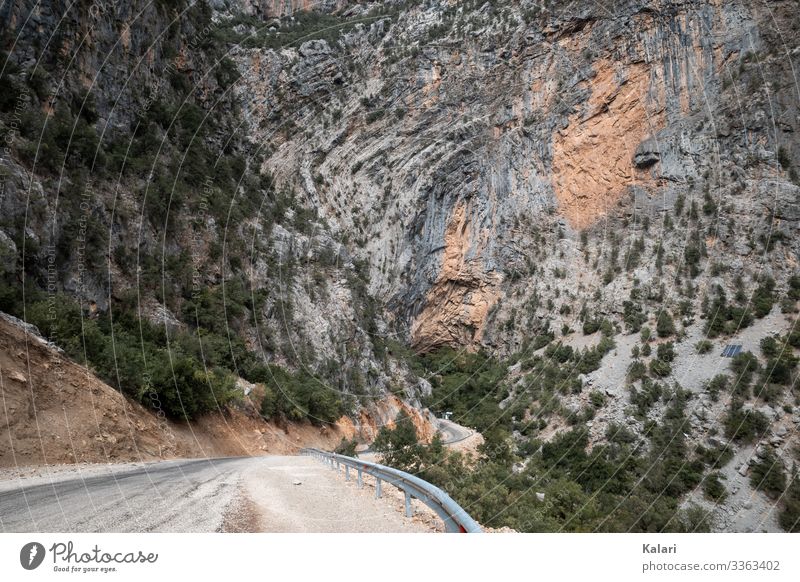 Gewundene Strasse in den Bergen führt auf eine Felswand zu strasse fels berg felswand fahrt route weg landschaft karg panorama natur himmel türkei blau anreisen