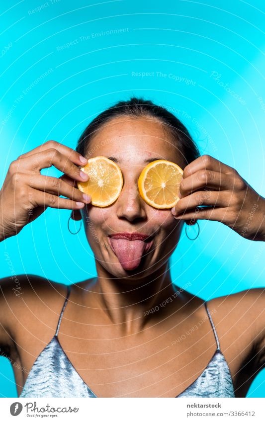 Junge Frau, die ihre Augen mit Zitronenscheiben bedeckt und ihre Zunge herausstreckt Scheibe ausspannen Mädchen Überfall Konzept herausstehende Zunge
