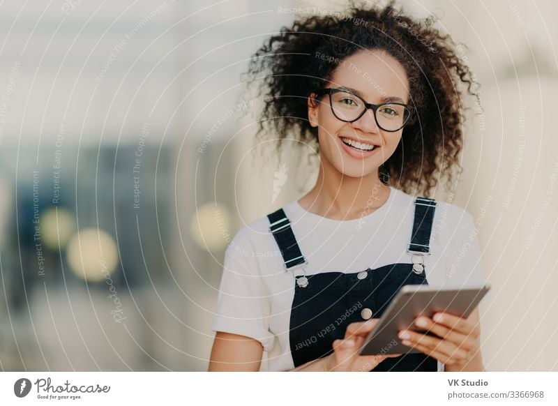 Liebliche dunkelhäutige ethnische Frau hält modernes Touchpad Lifestyle Freude Glück Technik & Technologie Internet Erwachsene E-Mail T-Shirt Hemd Brille