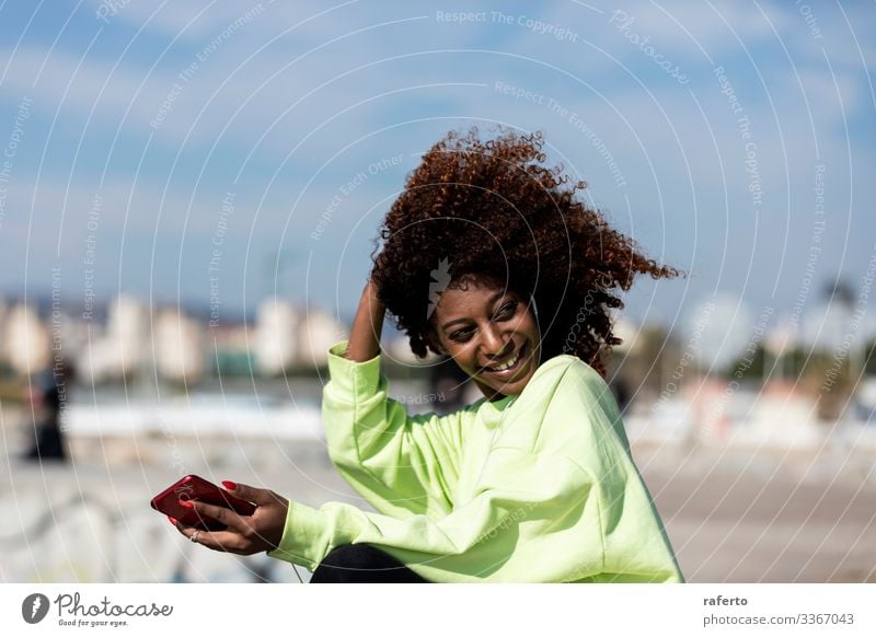 Schöne Afro-Frau sitzt an der Küste und benutzt ein Mobiltelefon Stil Glück schön Strand Telefon PDA Mensch feminin Junge Frau Jugendliche Erwachsene 1