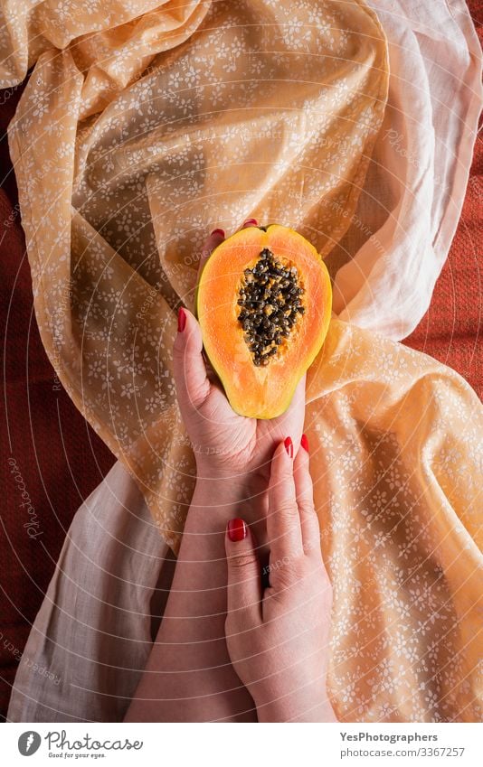 Papaya halb in Frauenhänden auf Tischtüchern halten. Frucht Dessert Frühstück Bioprodukte Vegetarische Ernährung Diät exotisch Gesunde Ernährung süß orange