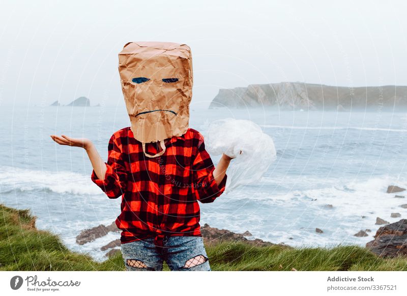 Person mit Papiertüte am Kopf, die Plastik hält Kunststoff Paket Ökologie Tüte Konzept Missbilligung nicht mögen nicht einverstanden sein Umwelt gestikulieren