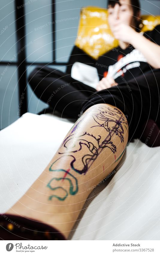 Frau mit übertragener Tätowierung auf dem im Salon liegenden Bein Tattoo transferieren Bild Schablone Skizze Klient Kosmetologie Haut Kosmetik Behandlung Farbe