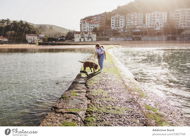 Frau mit Hund beim Spaziergang auf dem Steinpier Pier Gebäude Wasser MEER Zusammensein Haustier Küste Tier Lifestyle jung lässig Freundschaft Spanien lekeitio