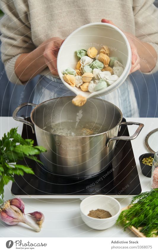Anonyme Köchin beginnt, Knödel mit buntem Teig zu kochen Essen zubereiten Fleisch kochend Topf Wasser farbenfroh Teigwaren Kraut mehrfarbig kulinarisch Prozess