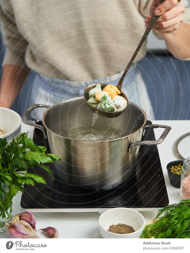 Anonyme Köchin beginnt, Knödel mit buntem Teig zu kochen Essen zubereiten Fleisch kochend Topf Wasser farbenfroh Teigwaren Kraut mehrfarbig kulinarisch Prozess