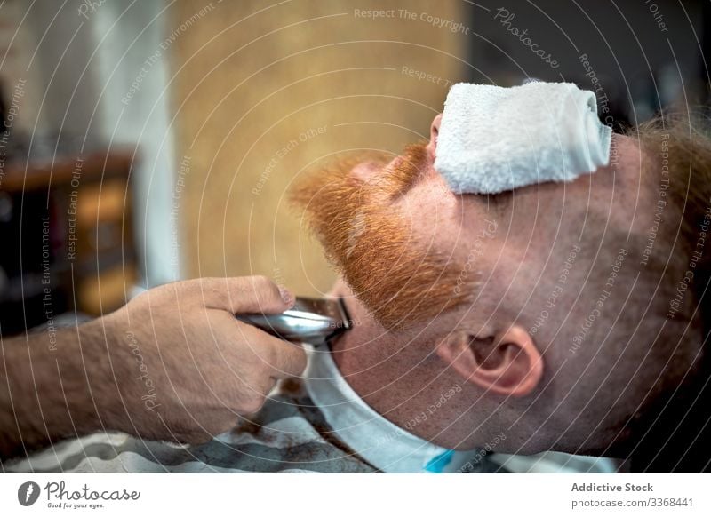Barbier schneidet rothaarigen Herrenbart Männer Klient trendy Friseur Barbershop Vollbart Maskulinität Kunde Pflege Salon gutaussehend stylisch entspannend