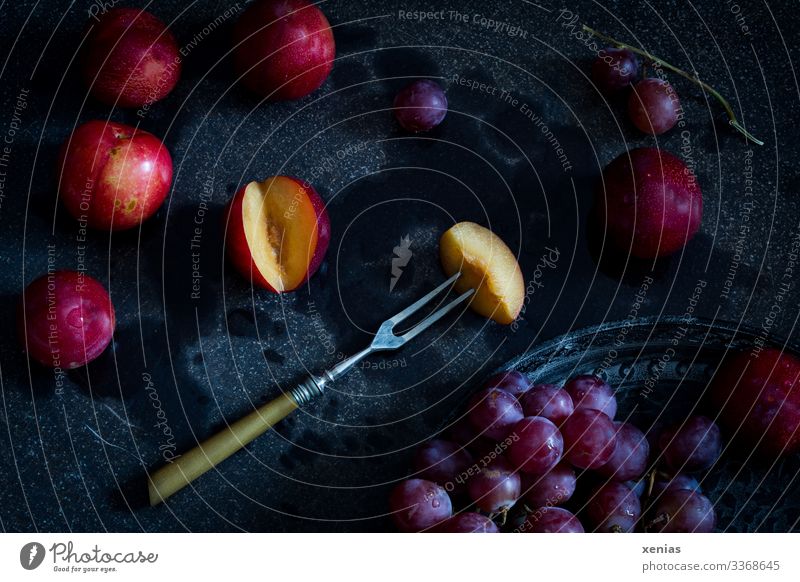 Nektarine mit Gabel und roten Weintrauben auf schwarzem Untergrund Frucht Ernährung Bioprodukte Vegetarische Ernährung Diät Gesunde Ernährung Lebensmittel