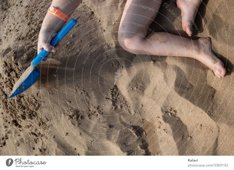 ein Kind spielt barfuß im Sand mit einer Schaufel spielen kind schaufel sand familienurlaub fuss sommer bein wasser spaß junge barfuss leute human natur hand