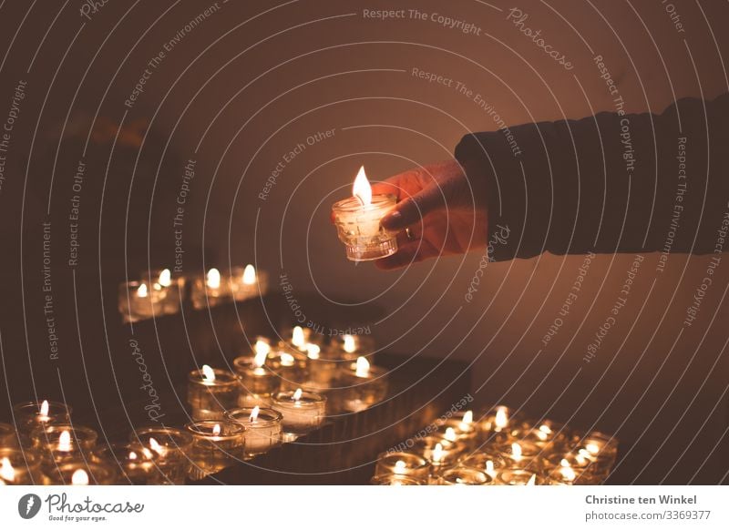 Frau zündet Kerze an einem Kerzenaltar an Erwachsene Hand 1 Mensch 30-45 Jahre 45-60 Jahre Kirche Kerzenschein Kerzenflamme Kerzenglas festhalten leuchten