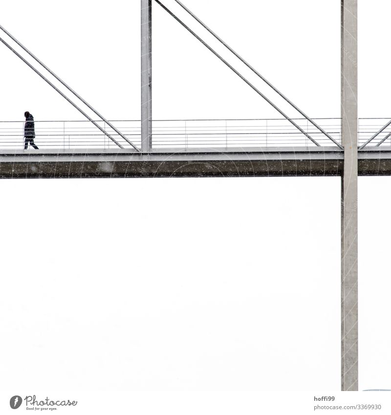 ein anonymer Mensch geht bei leichtem Schneefall über ein Fragment einer Brücke mit weissen Hintergrund 1 Winter schlechtes Wetter Nebel Hauptstadt