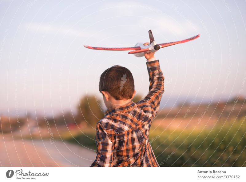 Kleiner Junge mit Spielzeugflugzeug beim Spielen im Freien Ferien & Urlaub & Reisen Abenteuer Kind Pilot Kindheit Blume Wiese Straße Flugzeug fliegen