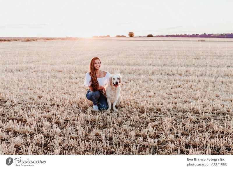 junge schöne Frau, die mit ihrem Golden Retriever-Hund auf dem Land genießt. Sommerzeit gelb Haustier Feld Sonnenuntergang Landschaft laufen im Freien Lifestyle