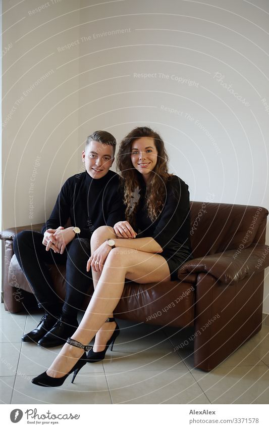 Junger Mann und junge Frau sitzen auf einer braunen Leder- Couch zusammen und lächeln Lifestyle Stil Freude schön harmonisch Wohnung Sofa Junge Frau Jugendliche