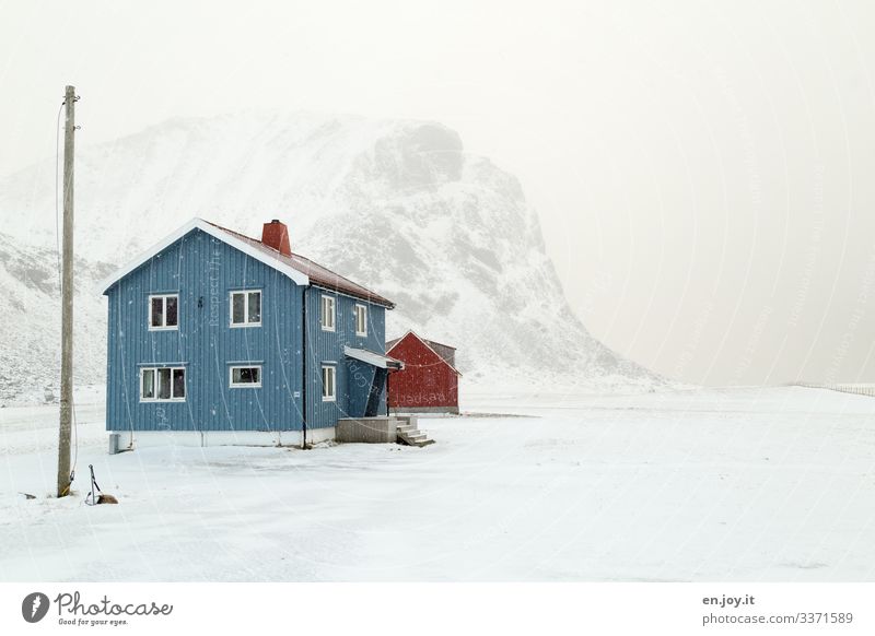 Blaues Haus im Schnee vor verschneitem Berg Norwegen Winter Lofoten Skandinavien Winterlandschaft Schneien Strom Strom Mast Stromversorgung Klima Klimawandel