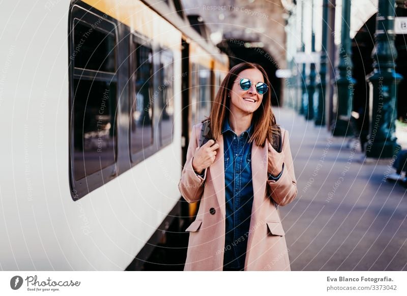 eine glückliche junge Frau, die am Bahnhof spazieren geht. Reisekonzept Bildschirm Ausflugsziel reisen Rucksack Kaukasier Europa Eisenbahn Warten Wagen Schiene