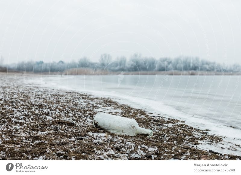 Glasflasche am Fluss am Wintermorgen Verlassen blau Flasche Nahaufnahme Küste kalt Land Tag Verwesung Schmutz dreckig auflösend Müllhalde Ökologie Umwelt Europa