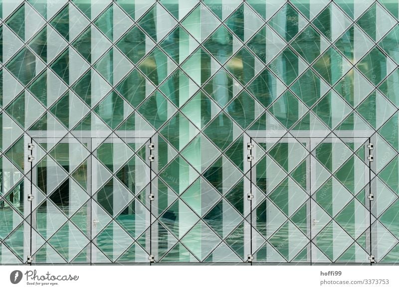 grün reflektierende transparente Fassade mit Türen und Schnee Glasfassade Spiegelung relektierend quadratisch Muster quadratische Struktur urban modern