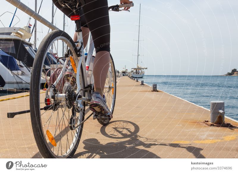 Detail einer Frau auf einem Fahrrad im Yachthafen von Rovinj, Istrien, Kroatien, an der Adria. Mitfahrgelegenheit Radfahren Fahrradfahren Übung Lifestyle Sport