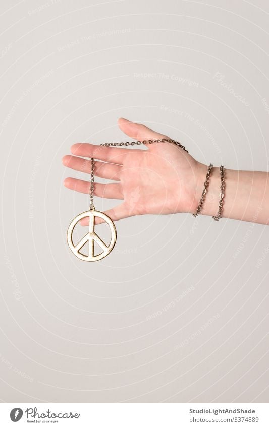 Weibliche Hand hält Friedenszeichen pazifik Arme Finger Frau Mädchen jung Halt Beteiligung Hippie Jugend gold golden grau rosa weiß anketten Armband Schmuck