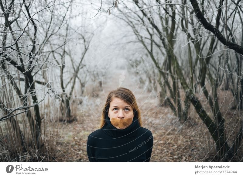Frau mit Klebeband am Mund im kalten Winterwald Erwachsener Angst Verhalten blond Kaukasier Zensur zivil Konzepte Depression Verzweiflung verzweifelt emotional