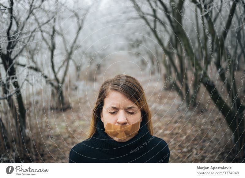 Frau mit Klebeband am Mund im kalten Winterwald Erwachsener Angst Verhalten blond Kaukasier Zensur zivil Konzepte Depression Verzweiflung verzweifelt emotional