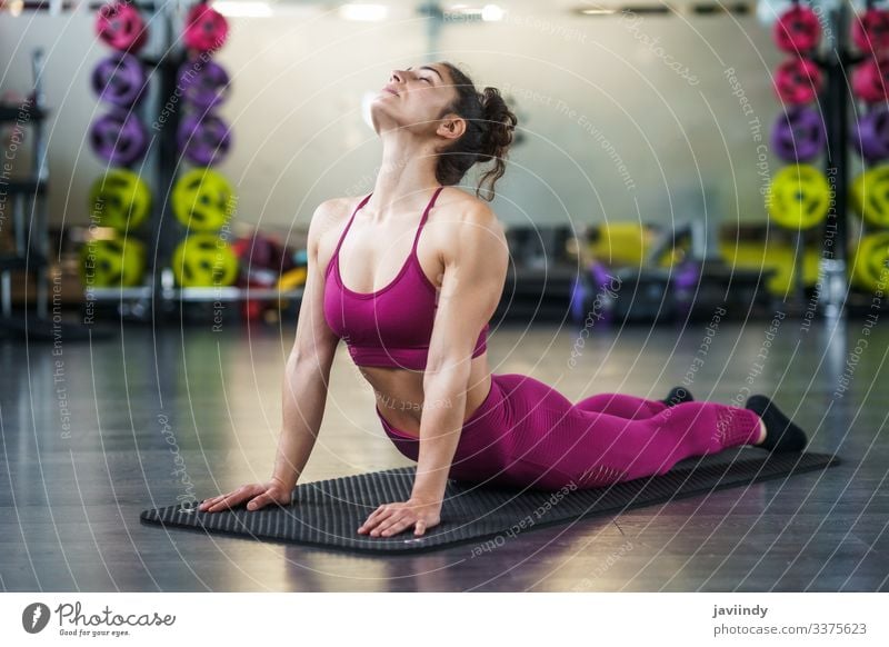 Junge Frau macht Dehnungsübungen auf einer Yogamatte strecken Unterlage Rücken Fitnessstudio Körper passen Bein Mädchen Sitzen Gesundheit Übung Lifestyle