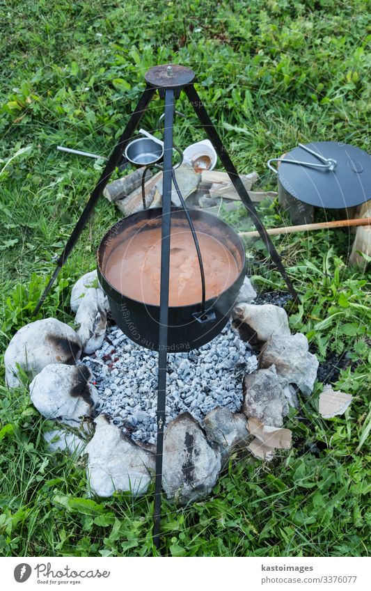 Gulasch, das bei einem Picknick in einem Kessel über offenem Feuer gekocht wird. schmoren Essen zubereiten Lebensmittel Speise Suppe Steine bügeln Feuerstelle