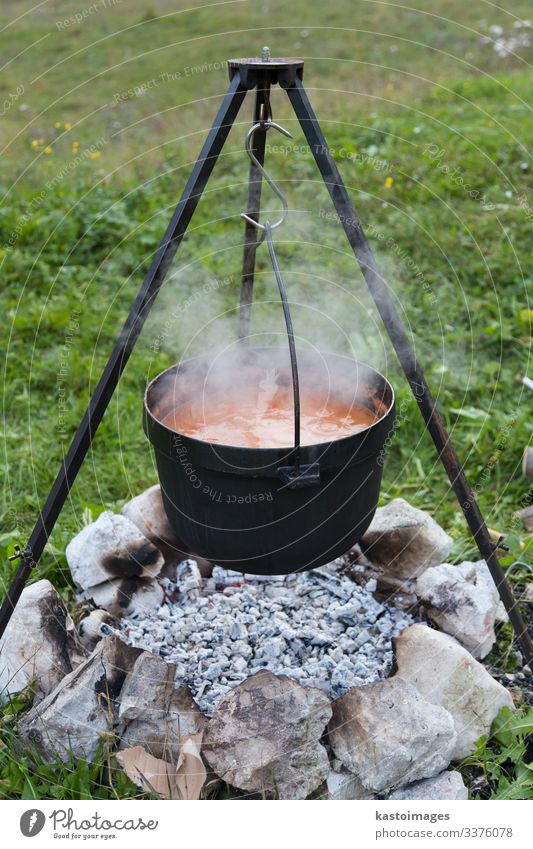 Gulasch, das bei einem Picknick in einem Kessel über offenem Feuer gekocht wird. Essen zubereiten lokale Küche gusseiserner Ofen Herd Gusseisen Kamin Steine