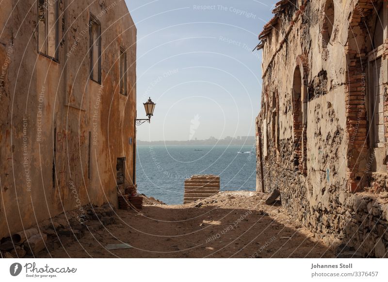 Blick zwischen Häuserschlucht von der Insel La Gorée auf Dakar Senegal Sklaveninsel Afrika Sonne Sand Meer Ocean Hafen Distanz Fähre Tourismus Urlaub Hitze