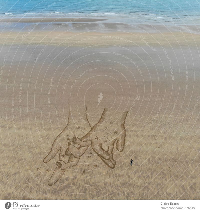Riesige Sandkunstzeichnung von Händchen haltend, erstellt mit Dji-Kamera Riese Hände Händchenhalten berührend Strand Küste nachhaltig Ökotourismus Umwelt Natur