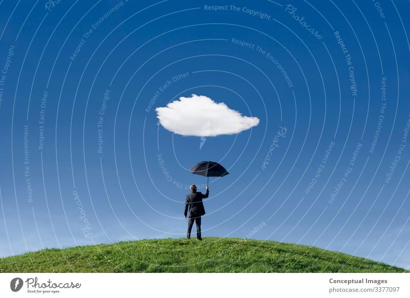 Geschäftsmann hält den Schirm unter einer einzigen Wolke Wolken Gras Hügel stehen Vorfreude Schutz Einsamkeit Gelassenheit Prognose Halt außerstädtische Szene